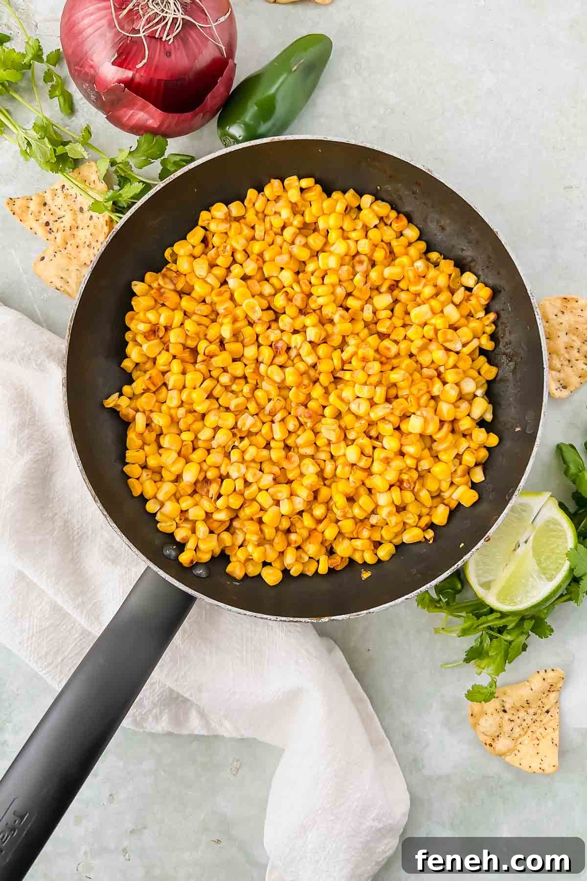 skillet filled with corn on green background and white linen.