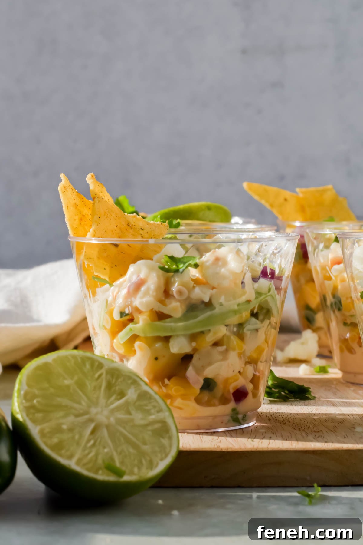 elote in a small glass cup with tortilla chips stuck in for serving.
