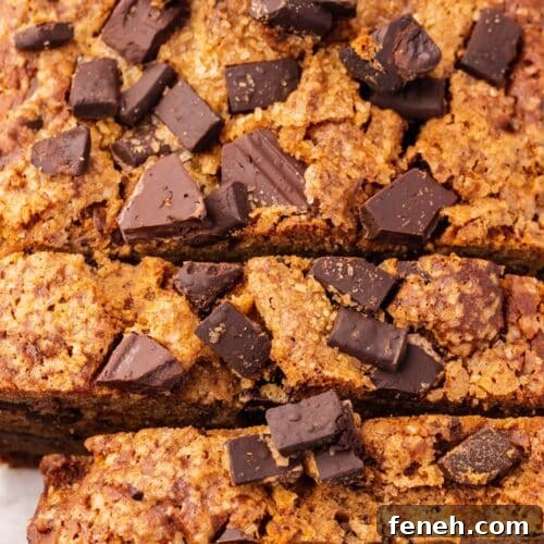 A closeup of a loaf of gluten-free vegan chocolate chunk banana bread that has been partially sliced.