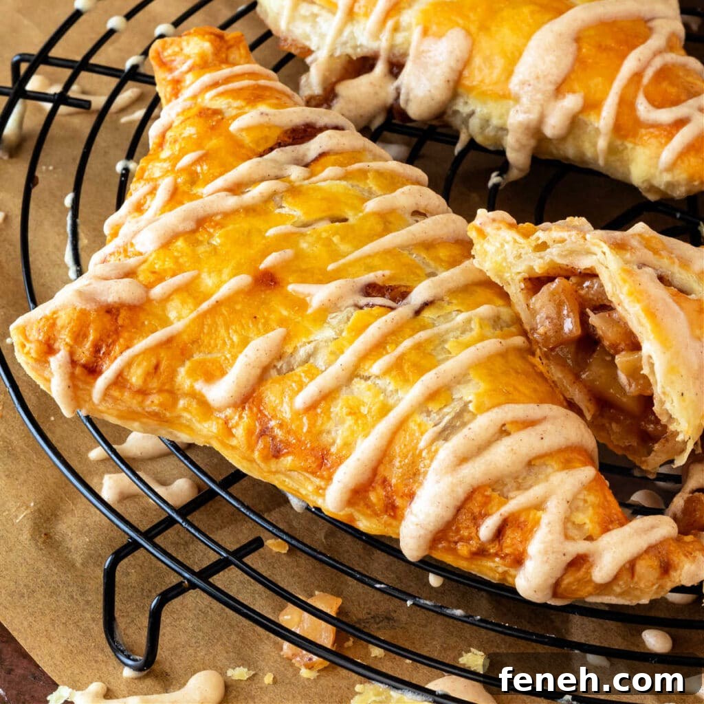 A close up of a triangular turnover with zigzags of glaze on it on a round, black, metal cooling rack.