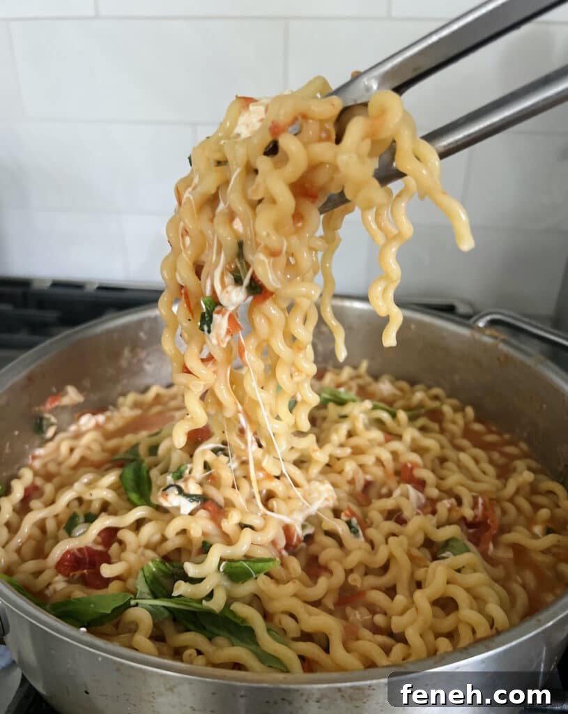 Tongs full of fusilli over pot full of finished recipe.