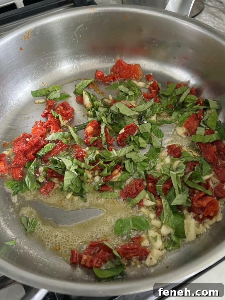 Fresh basil, dried tomatoes and garlic being sauteed in pan with butter.