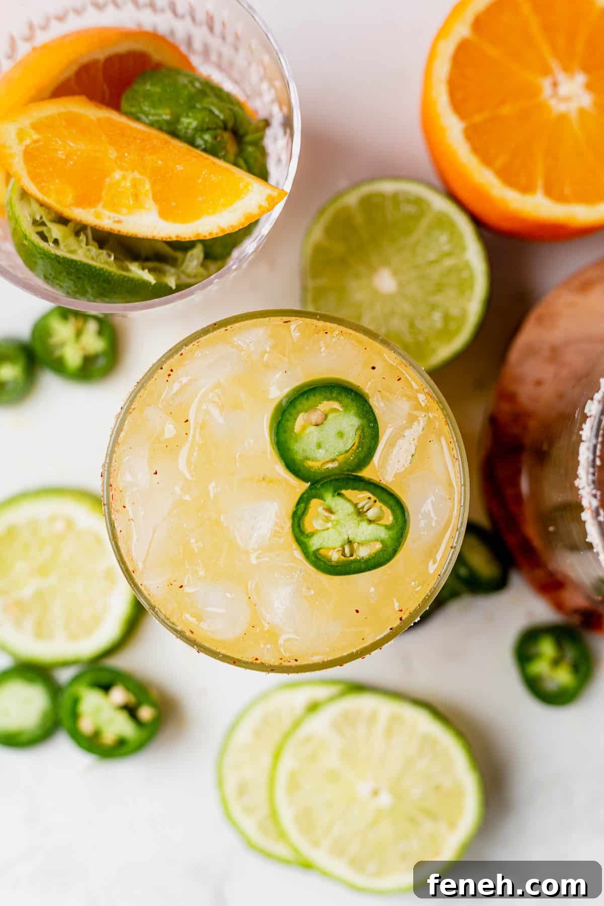 a glass full of a skinny spicy margarita with fresh limes and oranges