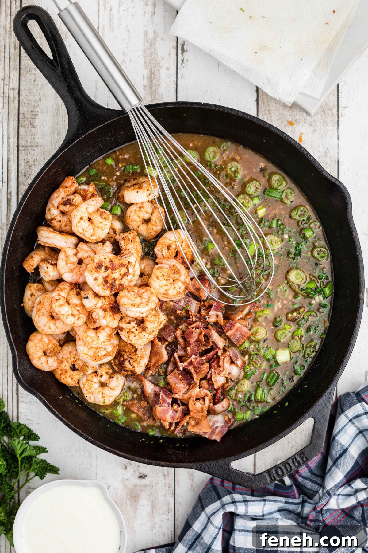 Shrimp and bacon added back to a cast iron skillet.