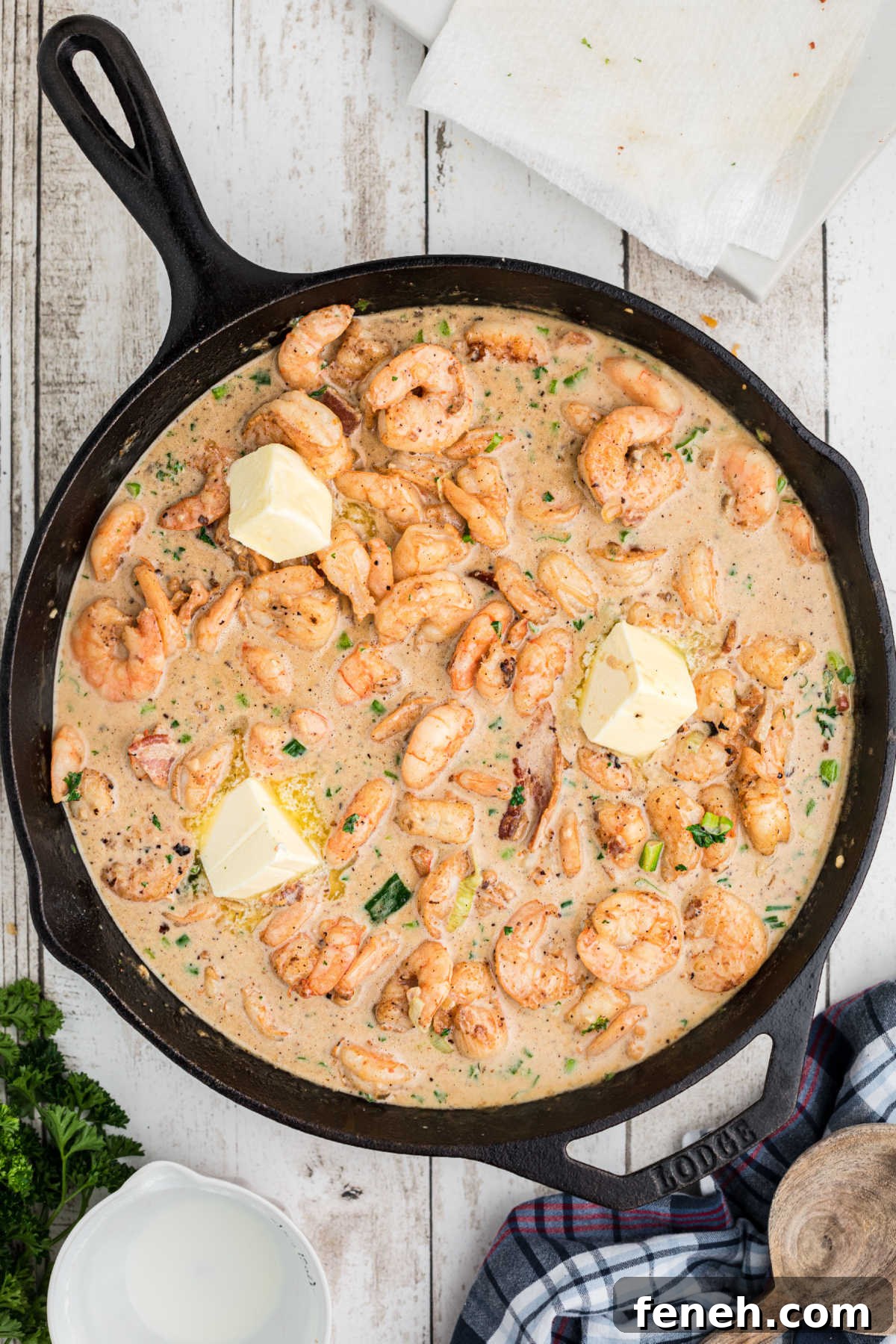 Butter pieces added to a shrimp recipe in a cast iron pan.
