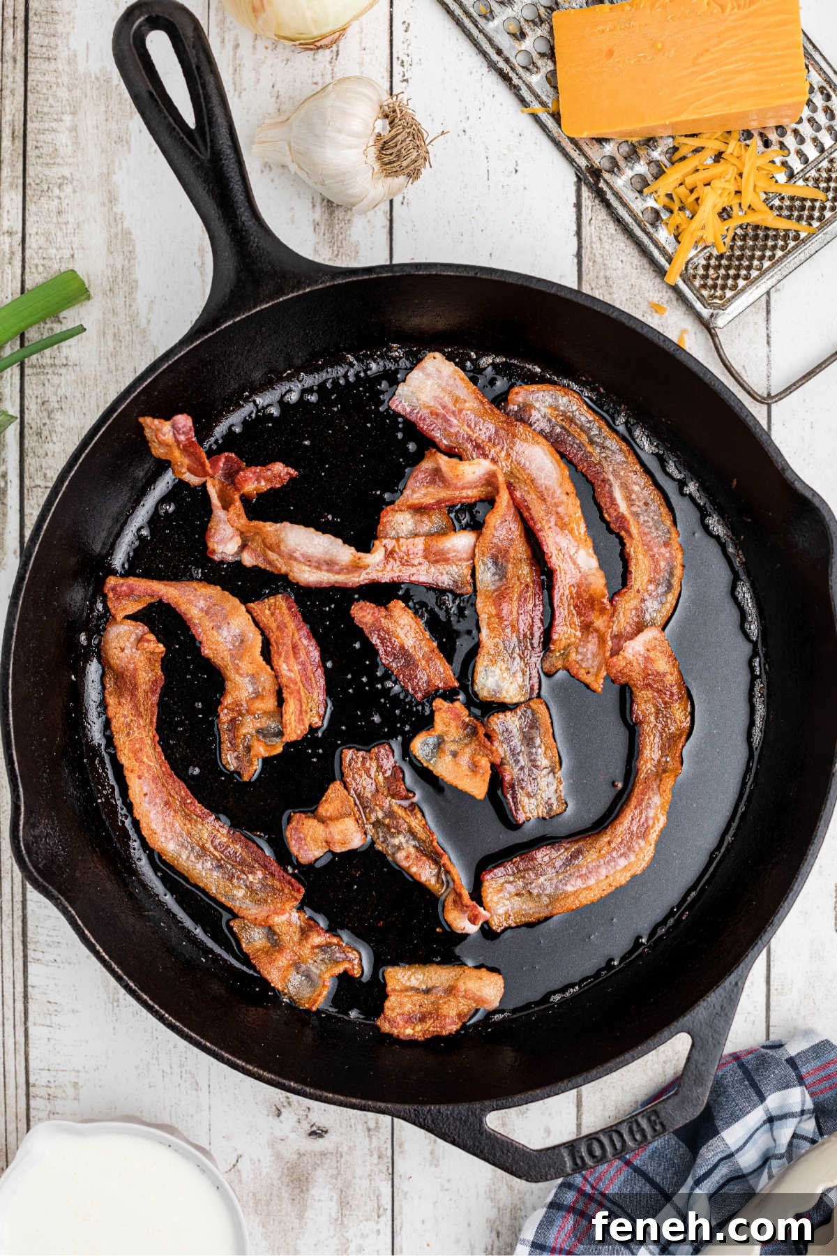 A large cast iron skillet with bacon cooking.