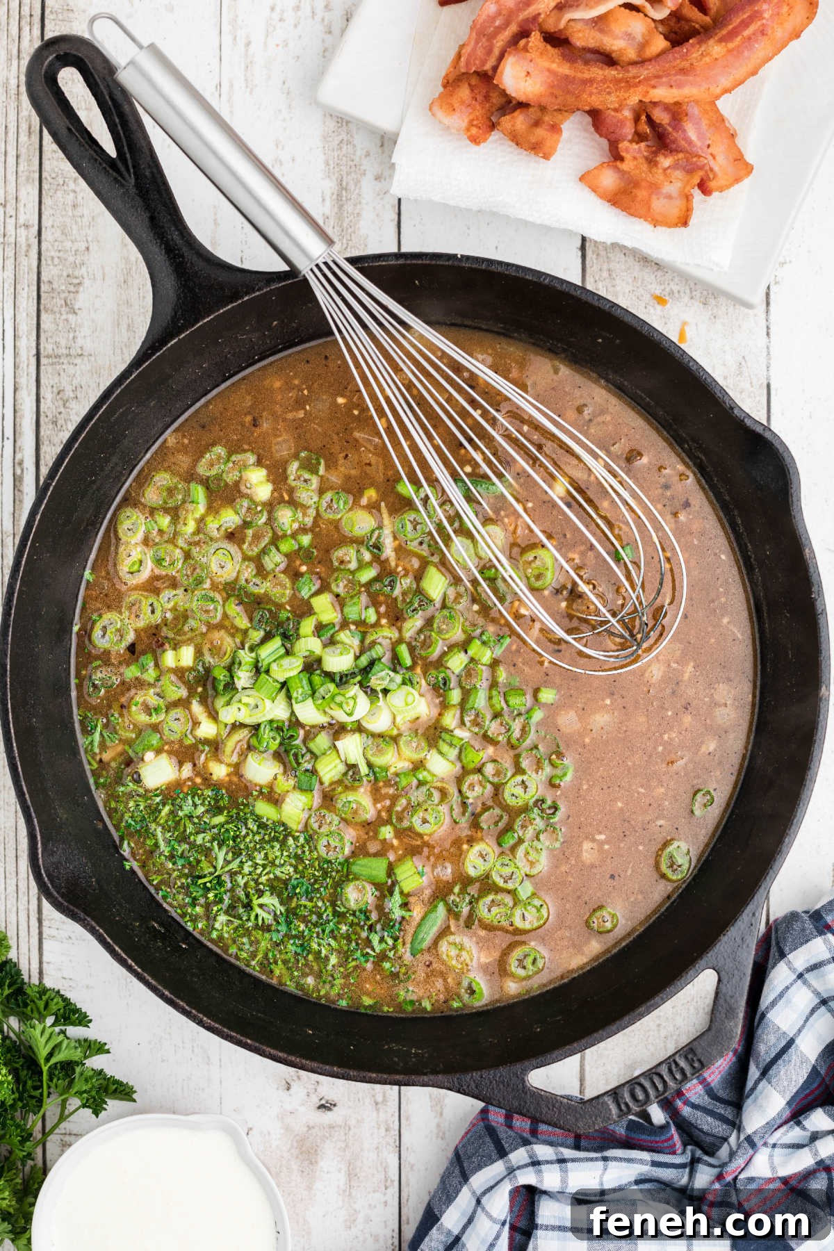 Green onions added to a skillet with a whisk.