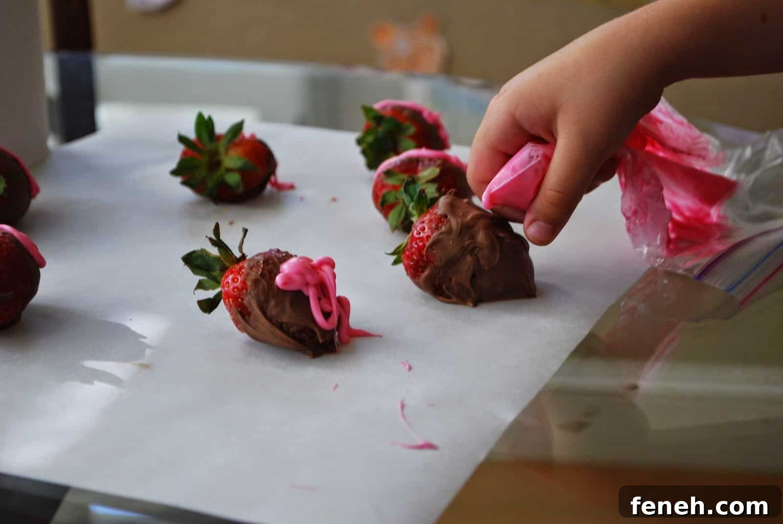 child drizzling candy melts on strawberry