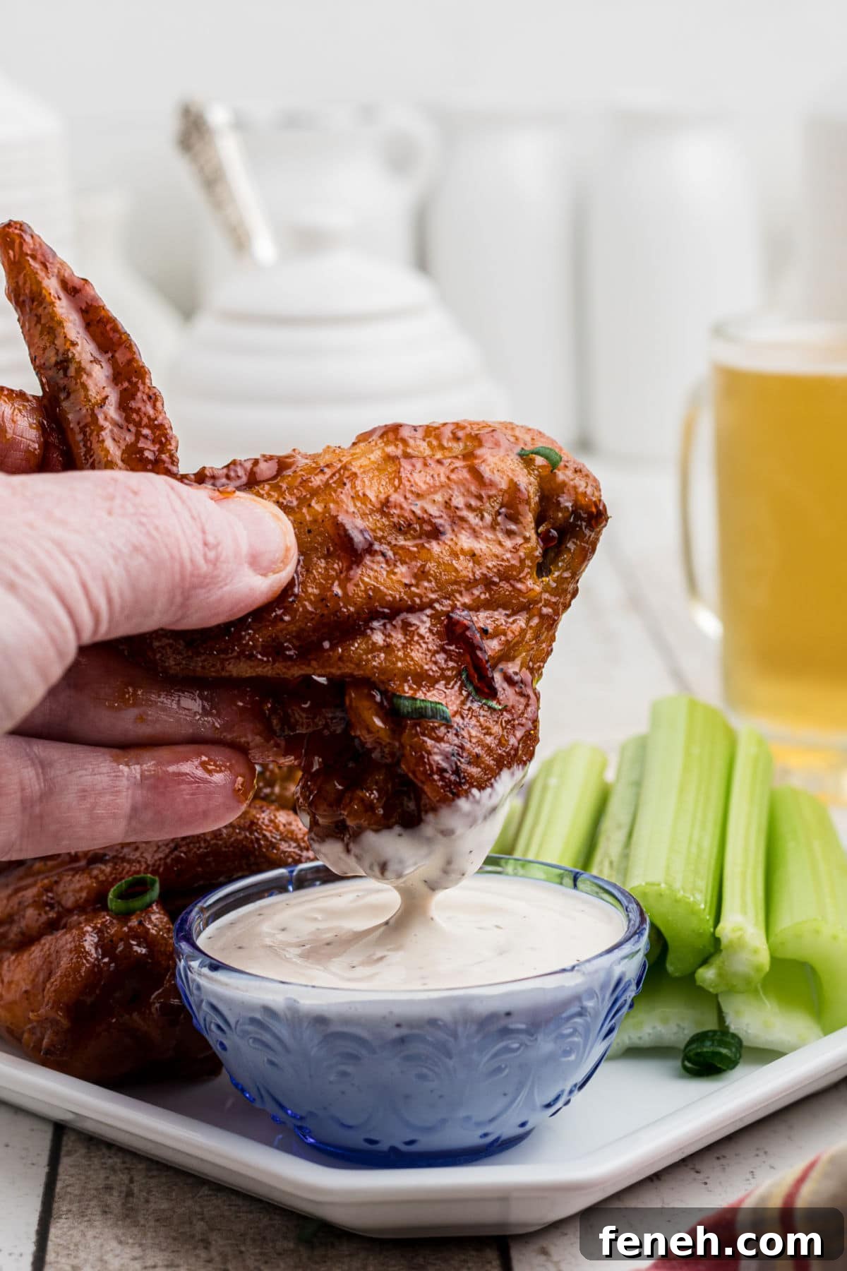 Someone dipping wings into Ranch dressing.