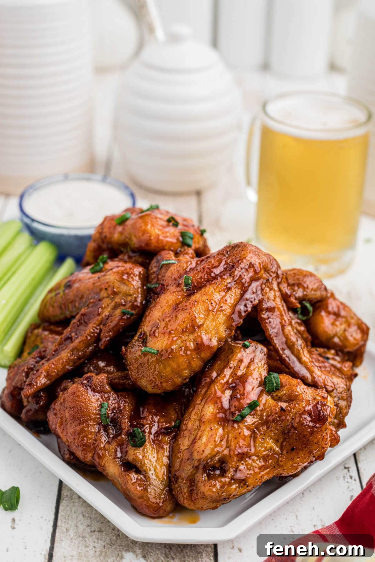 A platter of wings on a table with a glass of beer.