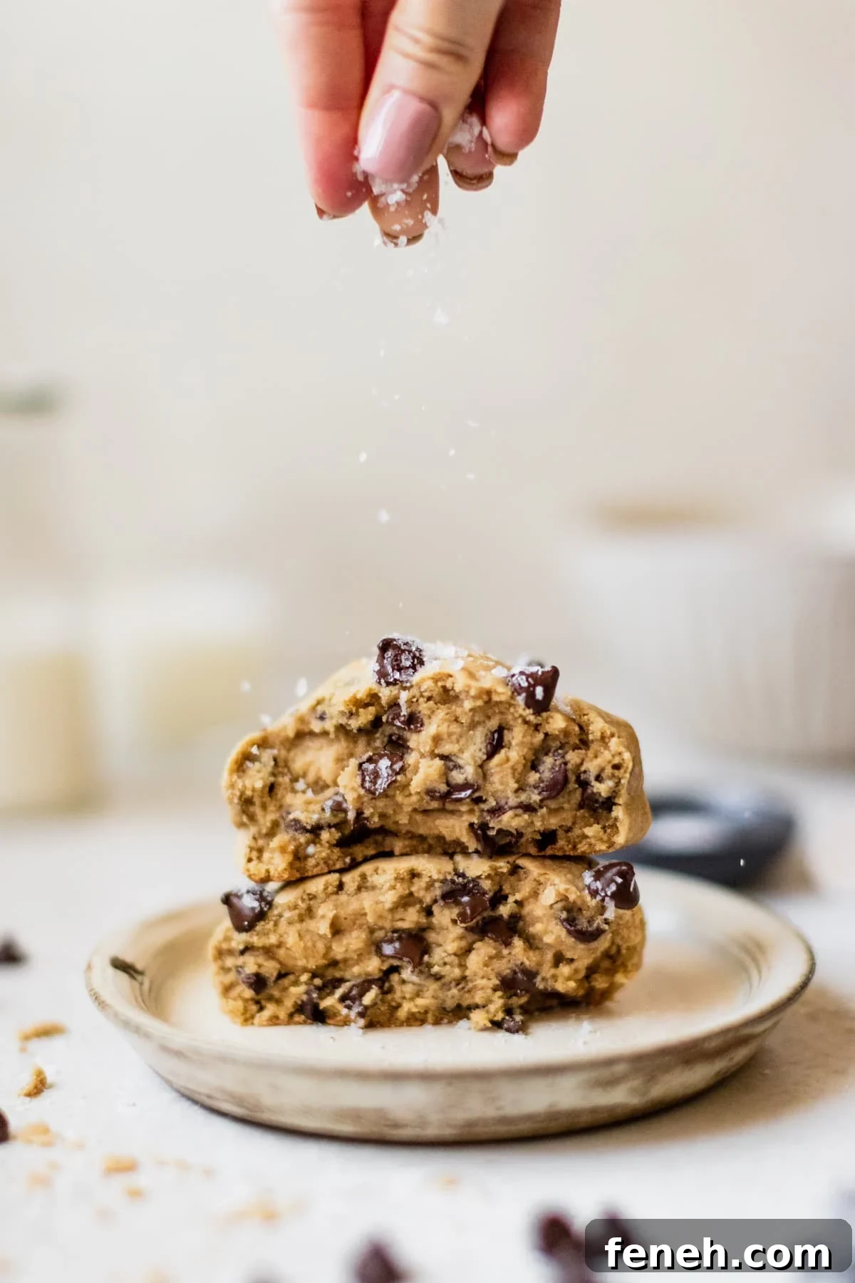 a chocolate chip cookie on a plate topped with sea salt.