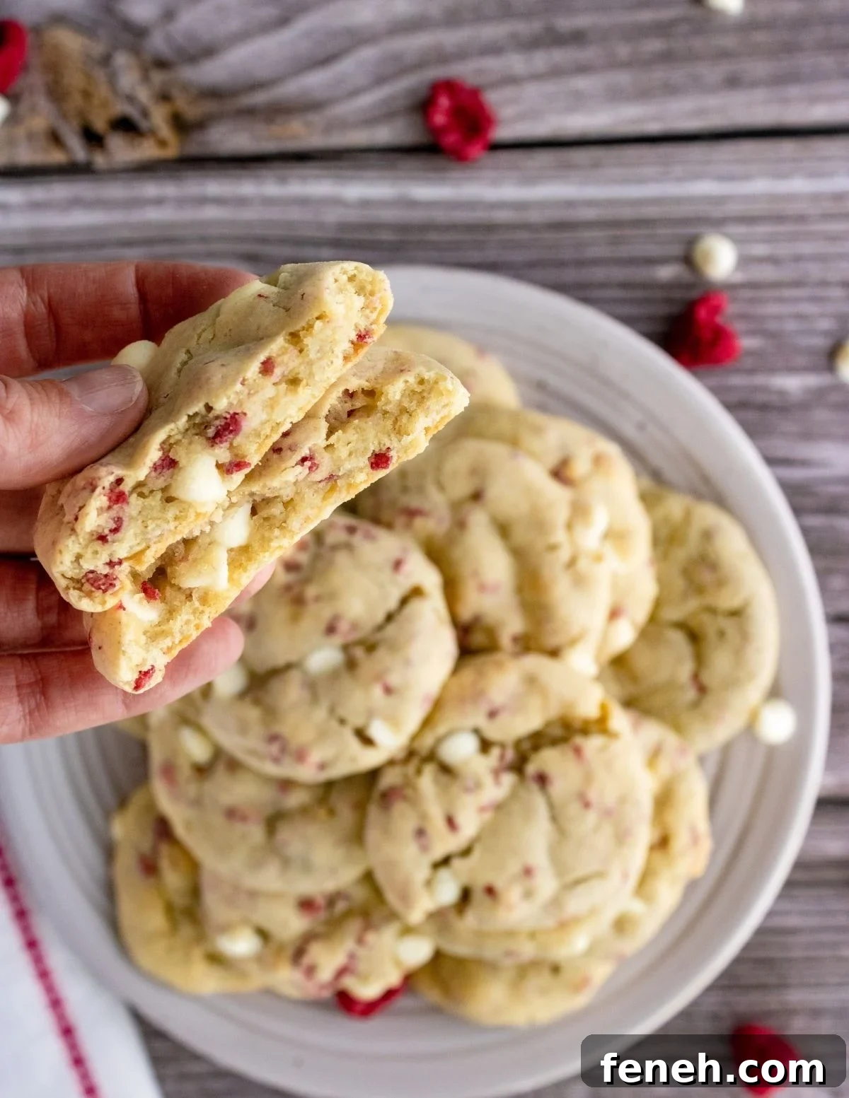raspberry cheesecake cookies torn in half and on a plate.