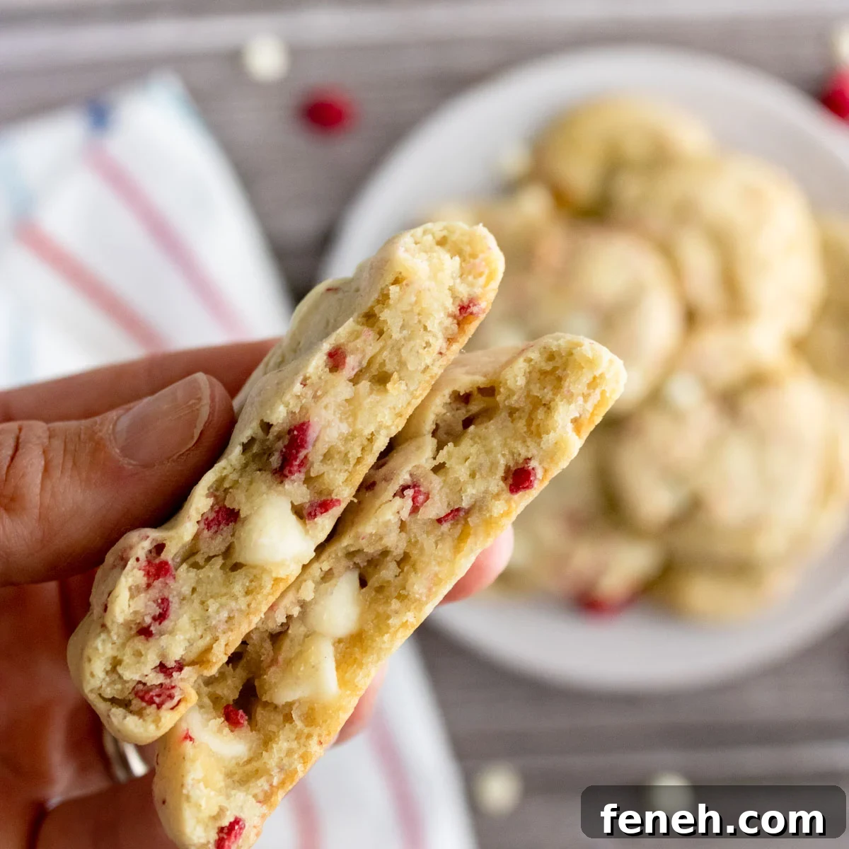 plate of raspberry cookies with one in a hand.