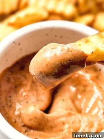 Dipping a french fry into homemade raising cane's sauce
