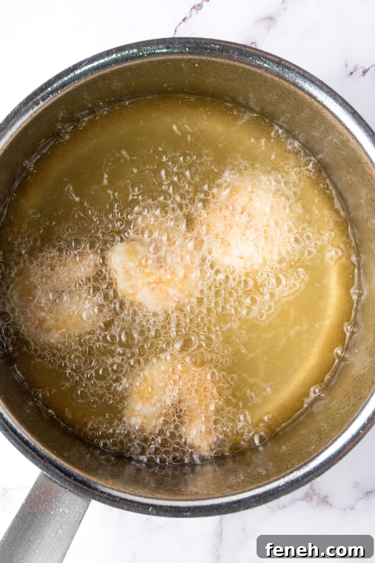 Deep frying shrimp in a pot of oil.
