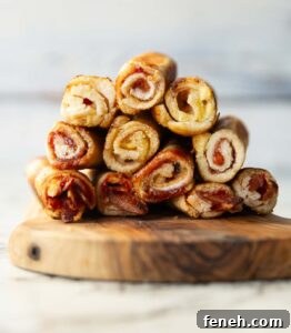 11 sandwich roll ups stacked on each other on wooden chopping board