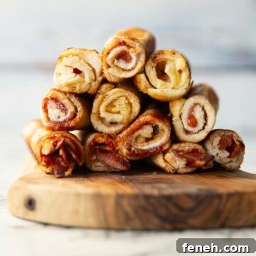 11 sandwich roll ups stacked on each other on wooden chopping board