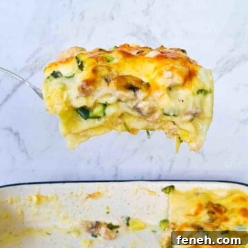 A slice of creamy chicken lasagna being scooped out of a baking tray