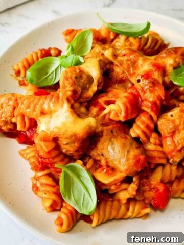 A plate of sausage pasta bake sprinkled with fresh basil
