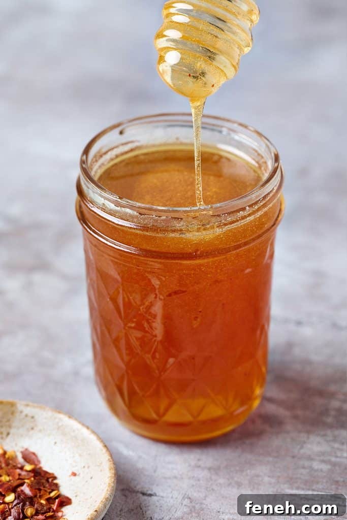 close up of honey honey drizzling from a dipper into a jar