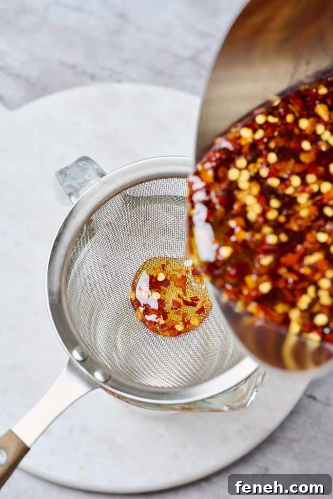 straining the honey with chili flakes
