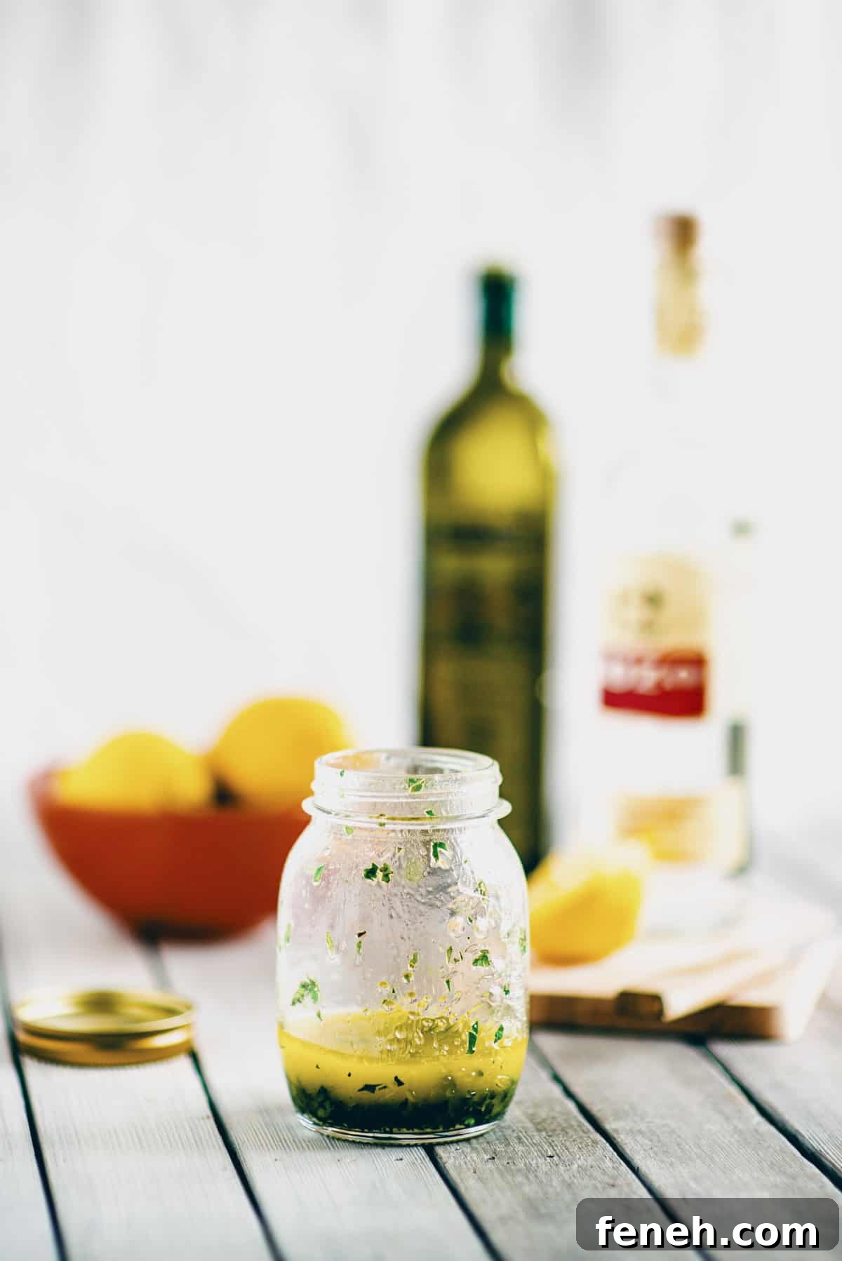 Greek salad dressing with ouzo in a glass jar on a wooden table with a soft blurred background.