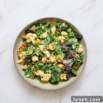 a bowl of roasted cauliflower salad on a white marble table.