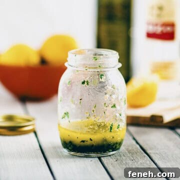 Greek salad dressing made with olive oil, lemon juice and herbs in a small glass jar.