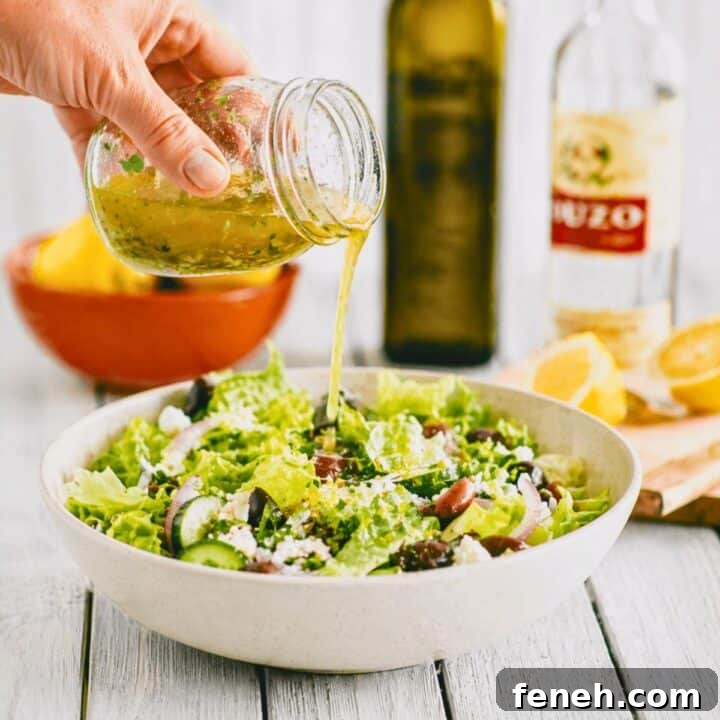 Greek salad dressing with ouzo being poured over a fresh salad with olives, cucumber and feta.