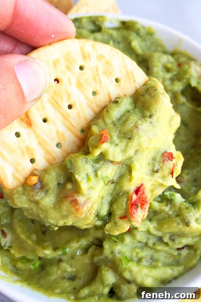 Cracker dipped in bowl of best homemade guacamole- Closeup shot. 