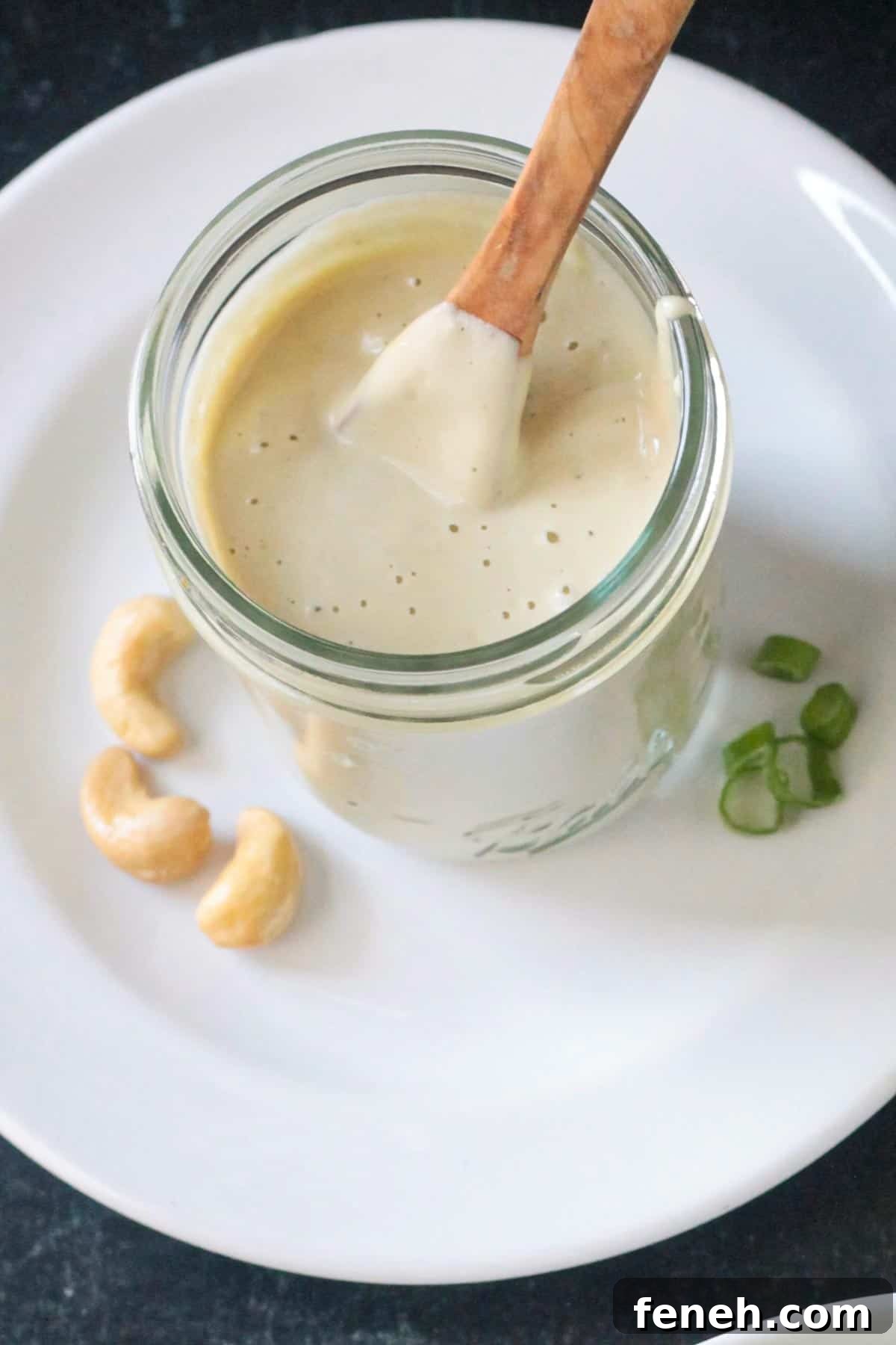 Small wooden spoon in a jar of creamy sesame salad dressing.