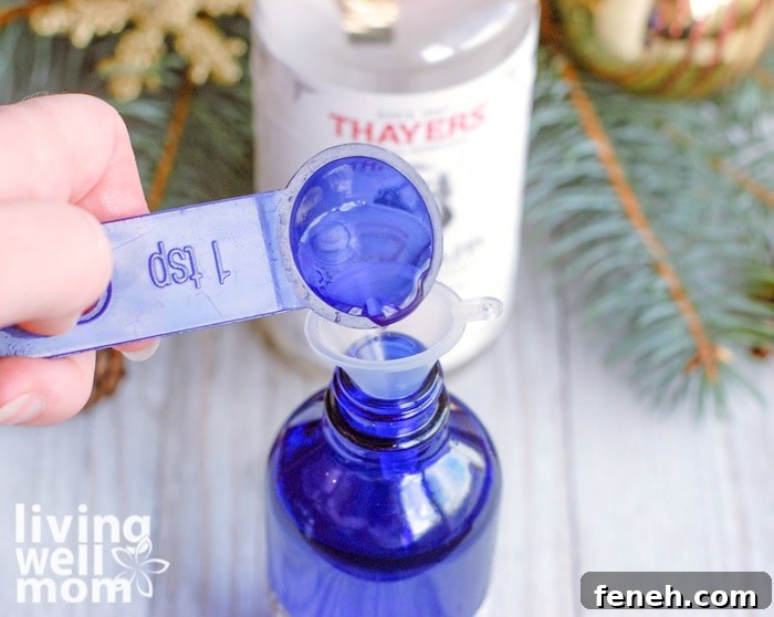 teaspoon of ingredients being added into blue glass bottle