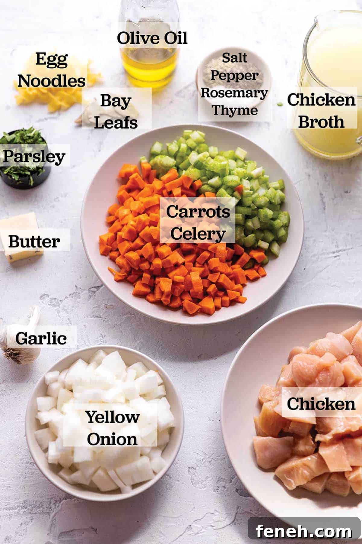 Ingredients to make a chicken noodle soup layer out in prep bowls and measuring cups.