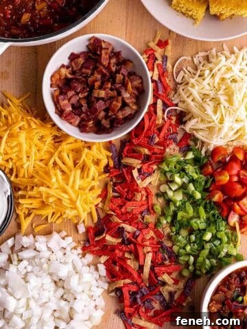 A wooden board with cheese, onions, tortilla chips, and a pot of chili.
