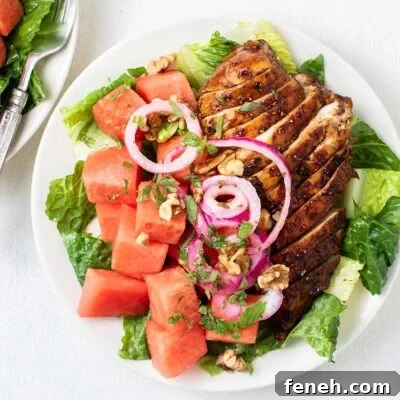 A close up look at a watermelon salad without feta topped with marinated onions, walnuts, and mint.
