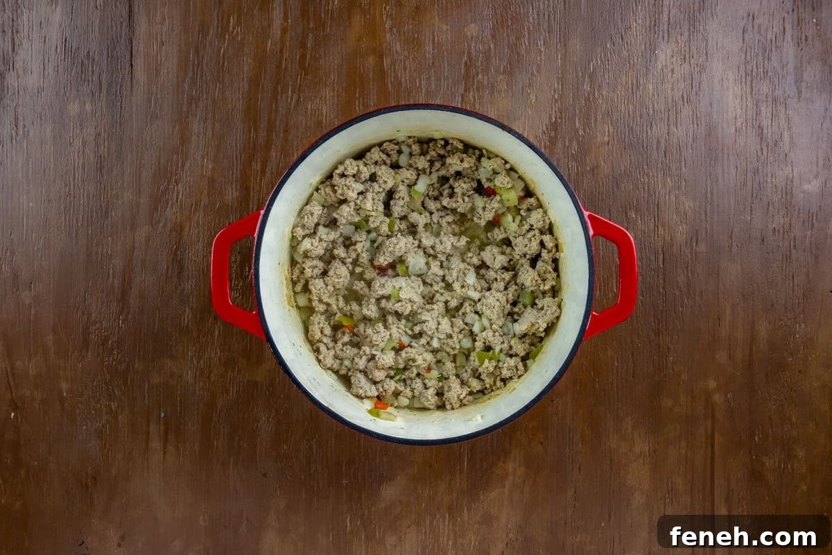 Chopped onion, belll pepper, and celery added to the cooked ground chicken in the dutch oven.