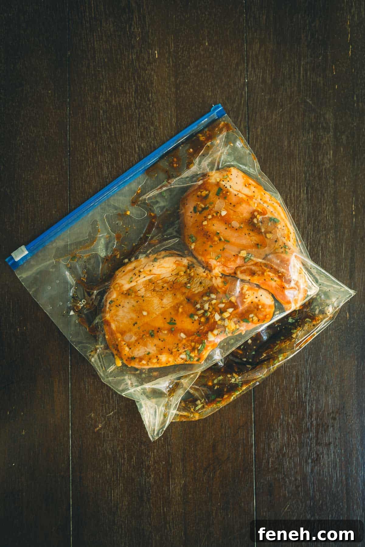 Bone-in pork chops marinating in a plastic bag.