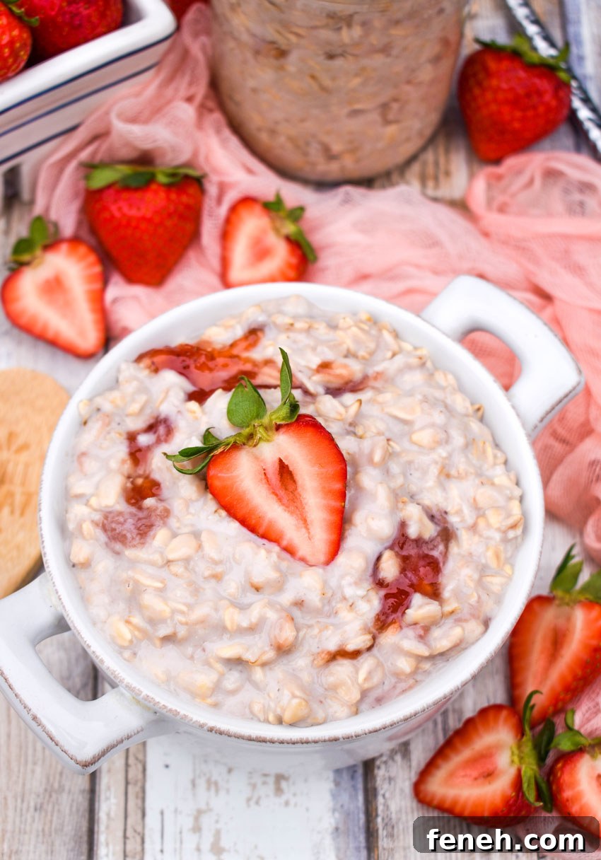 strawberries and cream overnight oats on a white bowl surrounded by fresh berries