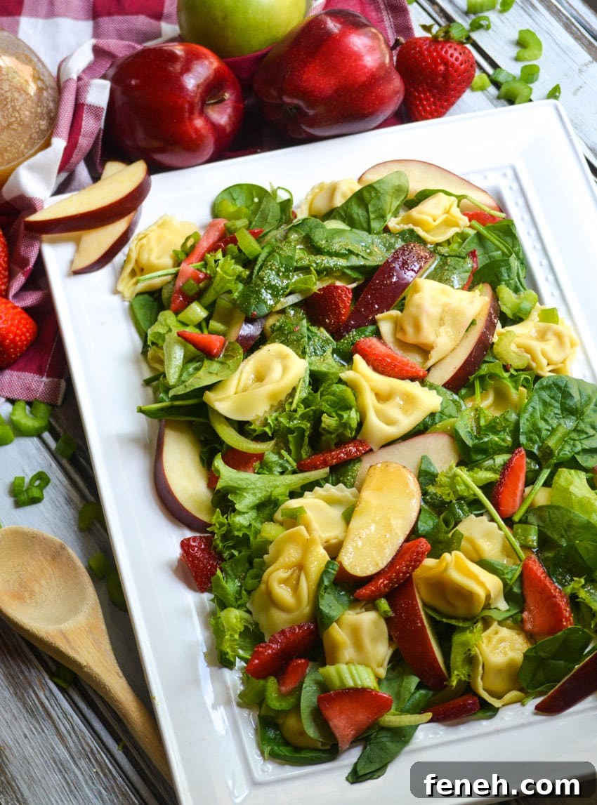 spinach tortellini salad with strawberries on a white serving platter