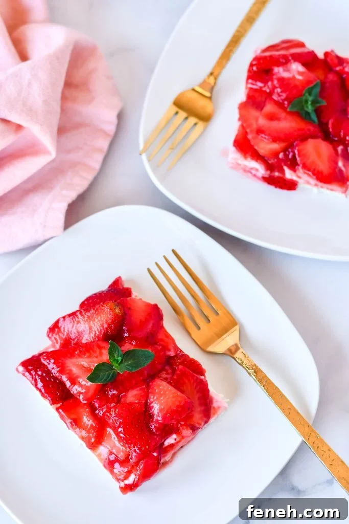 slices of strawberry slab pie on white plates with golden forks and a pink napkin in the background