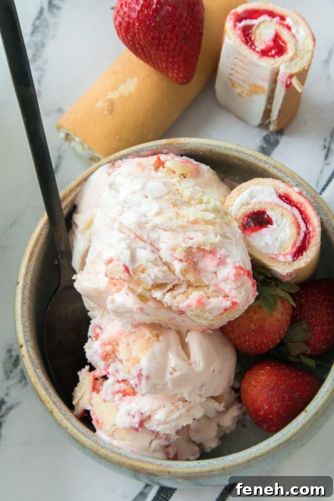 scoops of strawberry short cake rolls ice cream in a small gray bowl