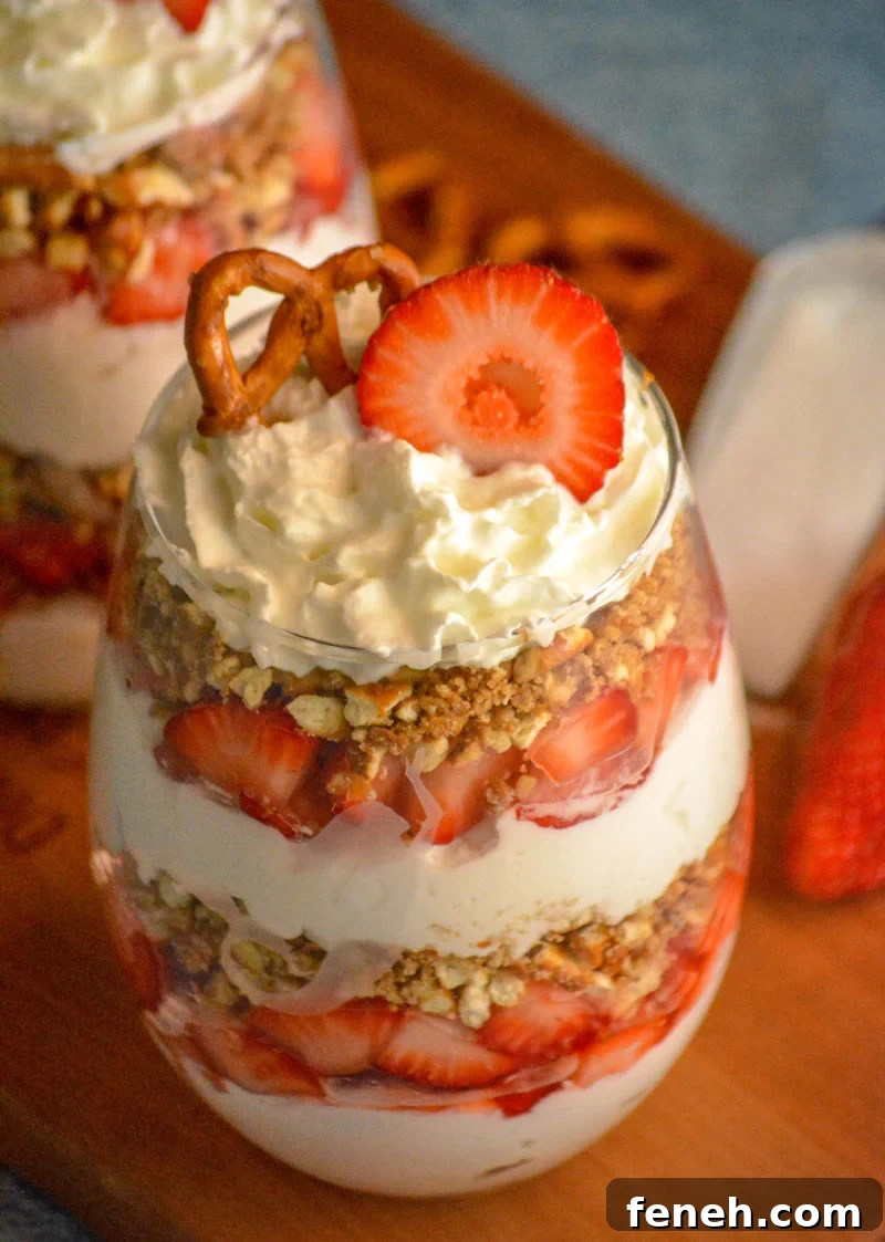 strawberry pretzel salad parfaits in glass jars on a wooden cutting board