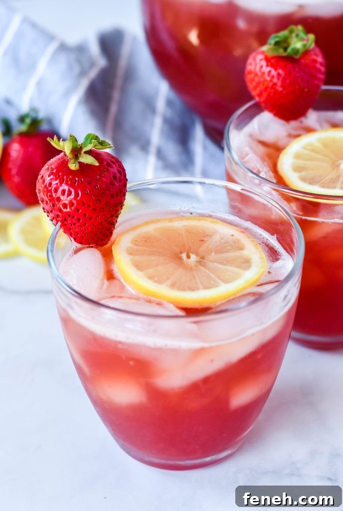 sweet strawberry iced tea served with sliced lemon and fresh strawberry for garnish