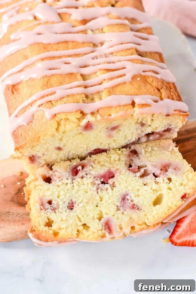 strawberry bread with cream cheese glaze served on a wooden cutting board on a marbled background