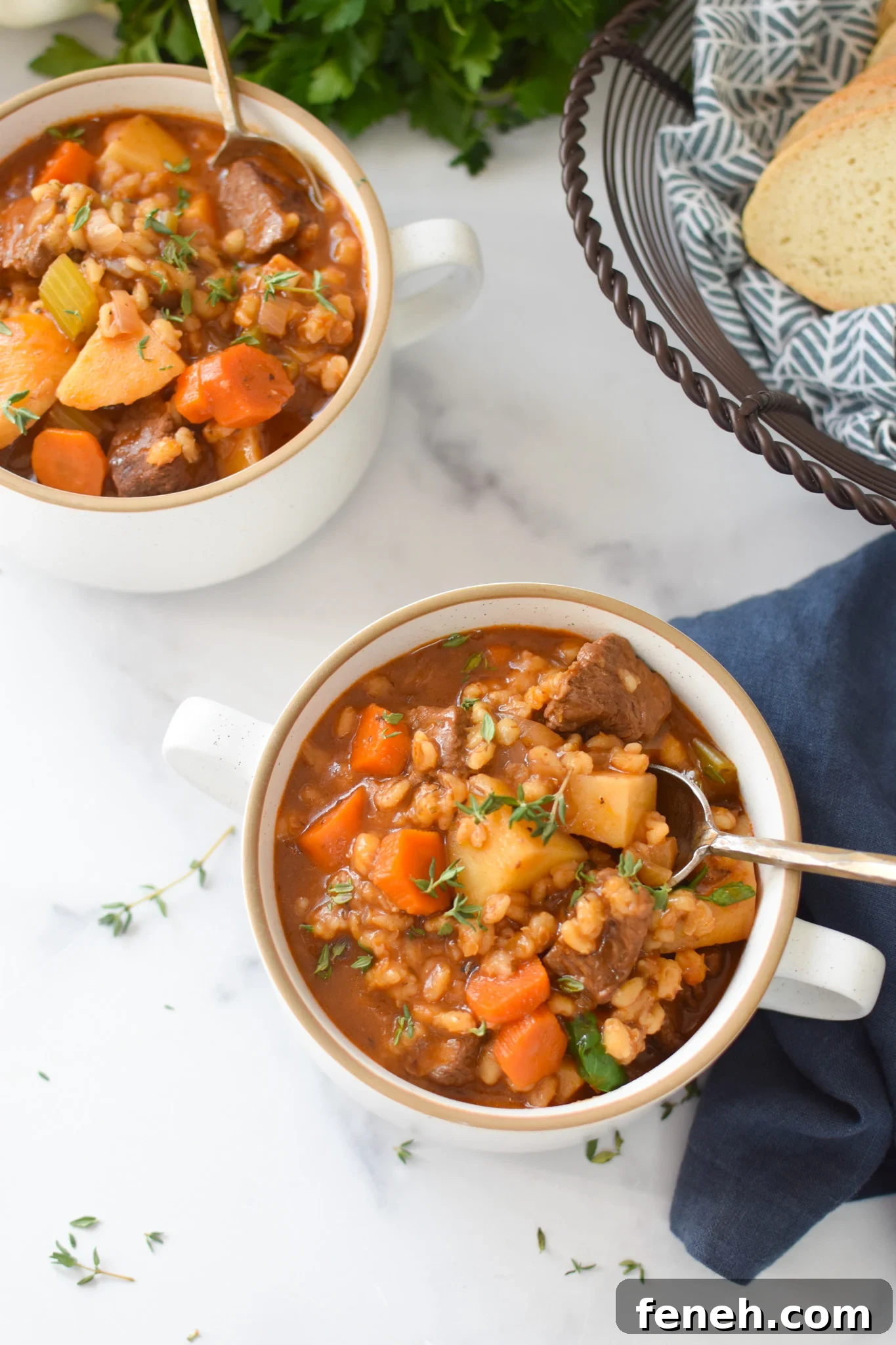 Slow Cooker Beef Barley Soup with spoon in a bowl on a white counter
