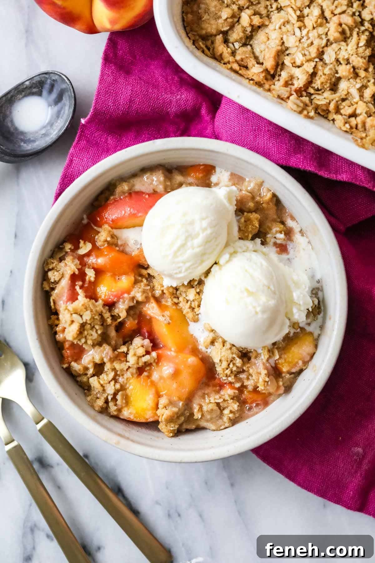 Overhead view of a bowl of peach crisp topped with vanilla ice cream.