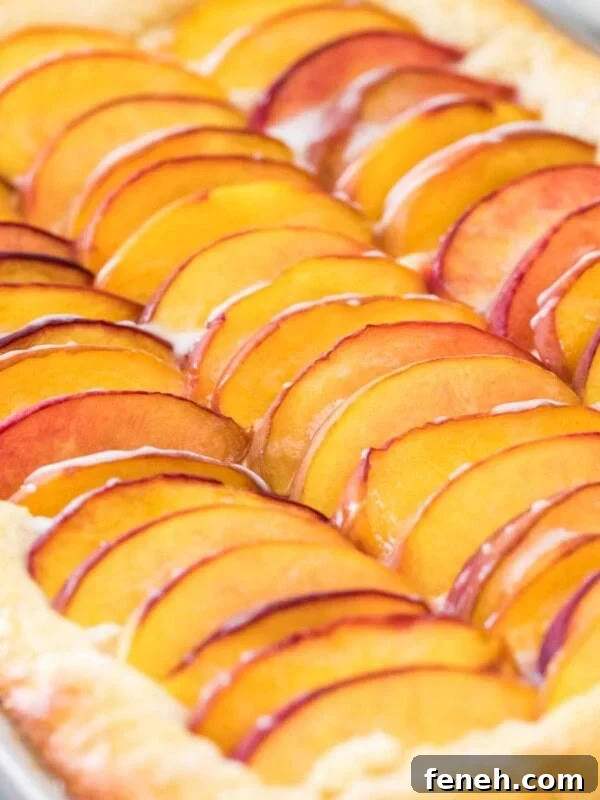 Close-up view of peach cake topped with sliced peaches in jellyroll pan