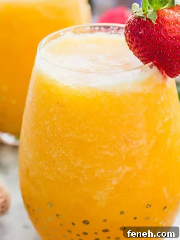 Frozen peach bellini in a glass with a strawberry garnish.