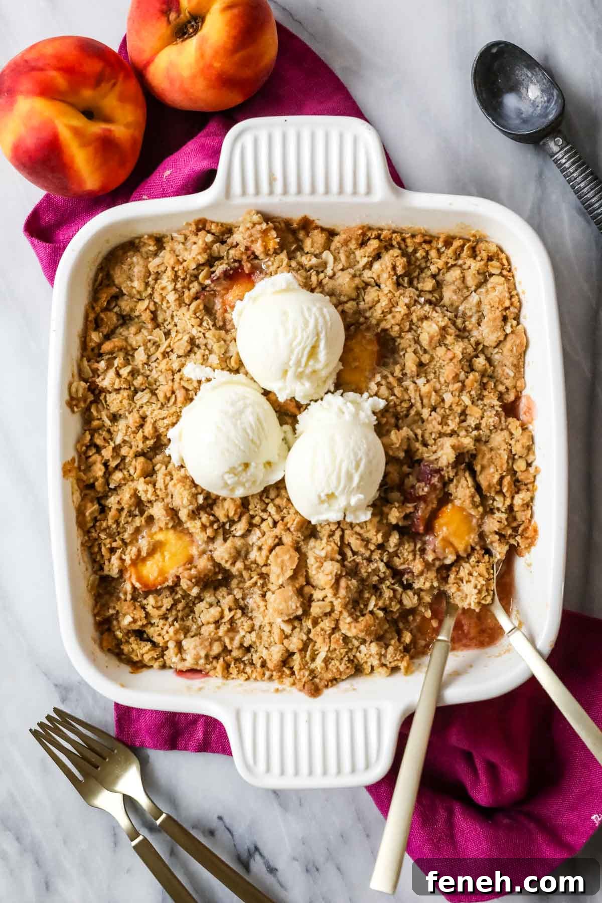 Overhead view of a peach dessert topped with an oat crumble and vanilla ice cream.