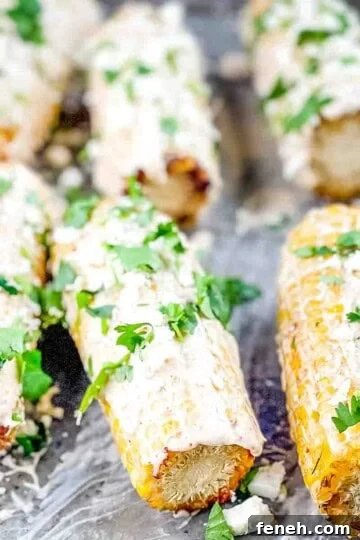 Authentic elote corn on a sheet pan, garnished with chopped cilantro.